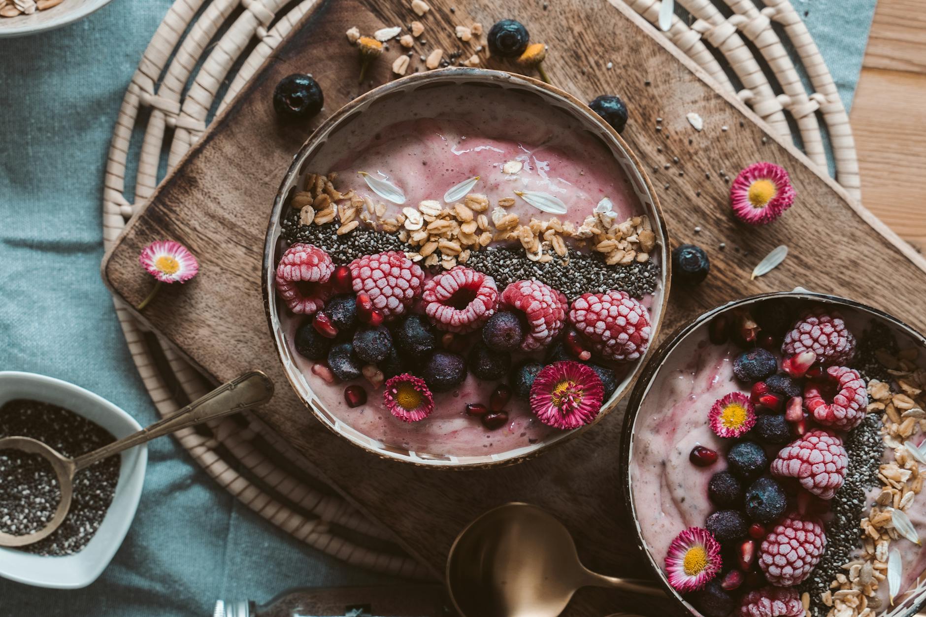 Kolorowe smoothie bowl z owocami, nasionami chia i granolą na stole