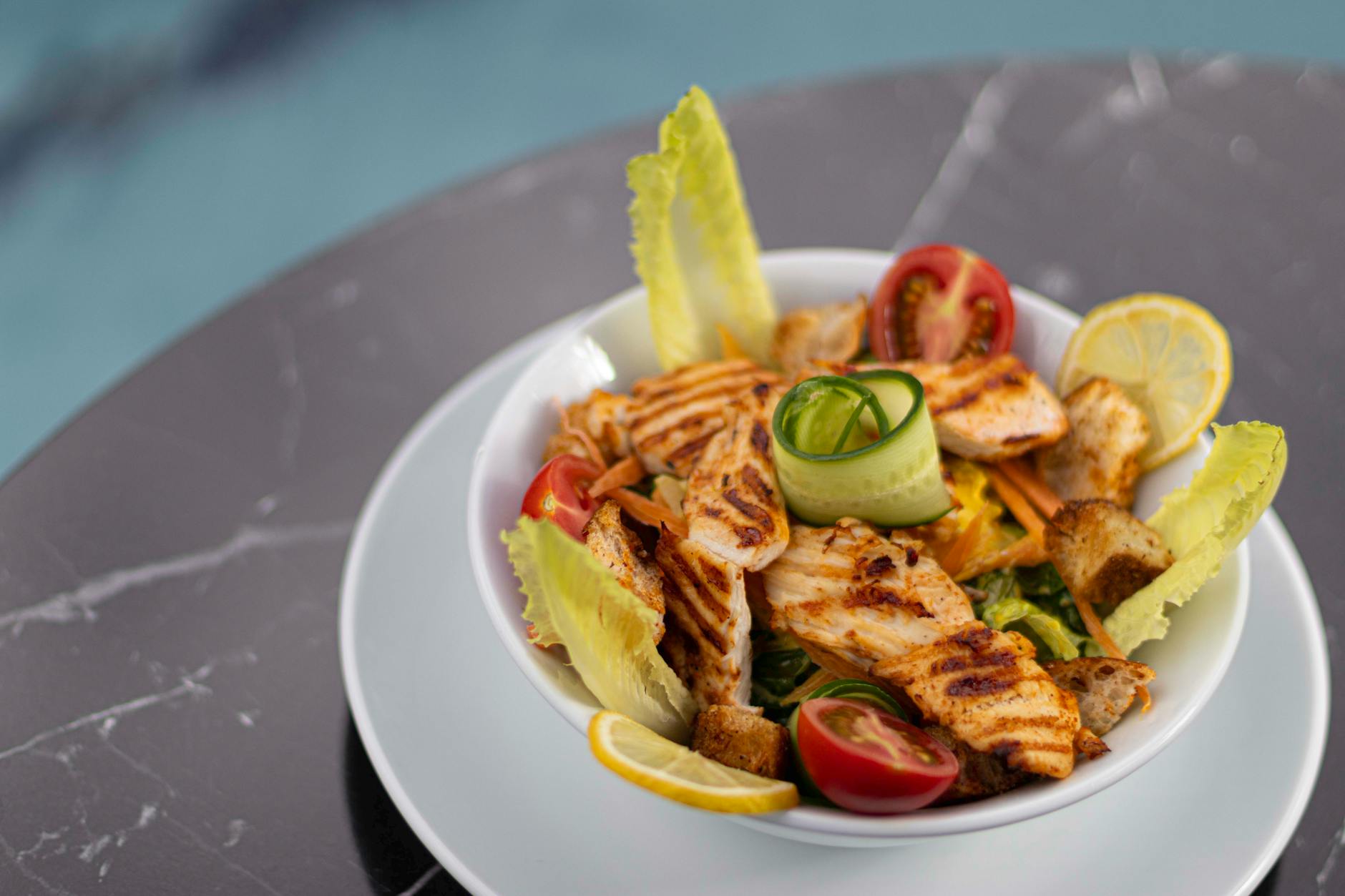 Sałatka Cezar z grillowanym kurczakiem i warzywami na marmurowym blacie
