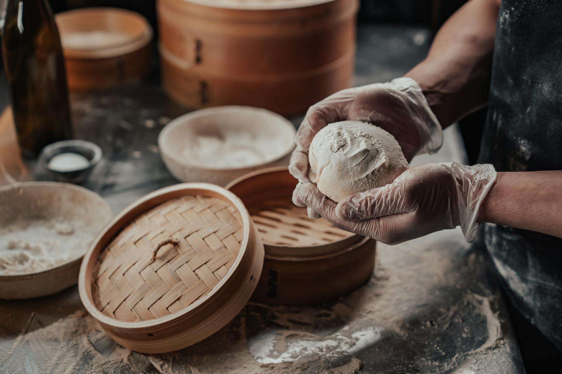 Dłonie zagniatają bezglutenowe ciasto na pierogi na oprószonym mąką blacie