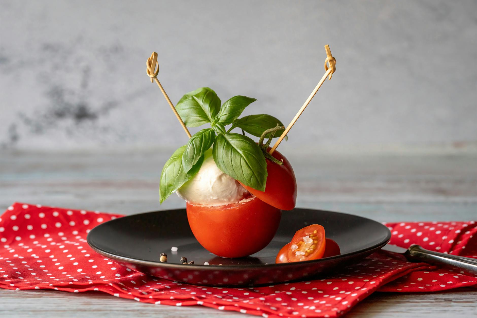 Sałatka caprese na talerzu z pomidorami, mozzarellą i świeżą bazylią